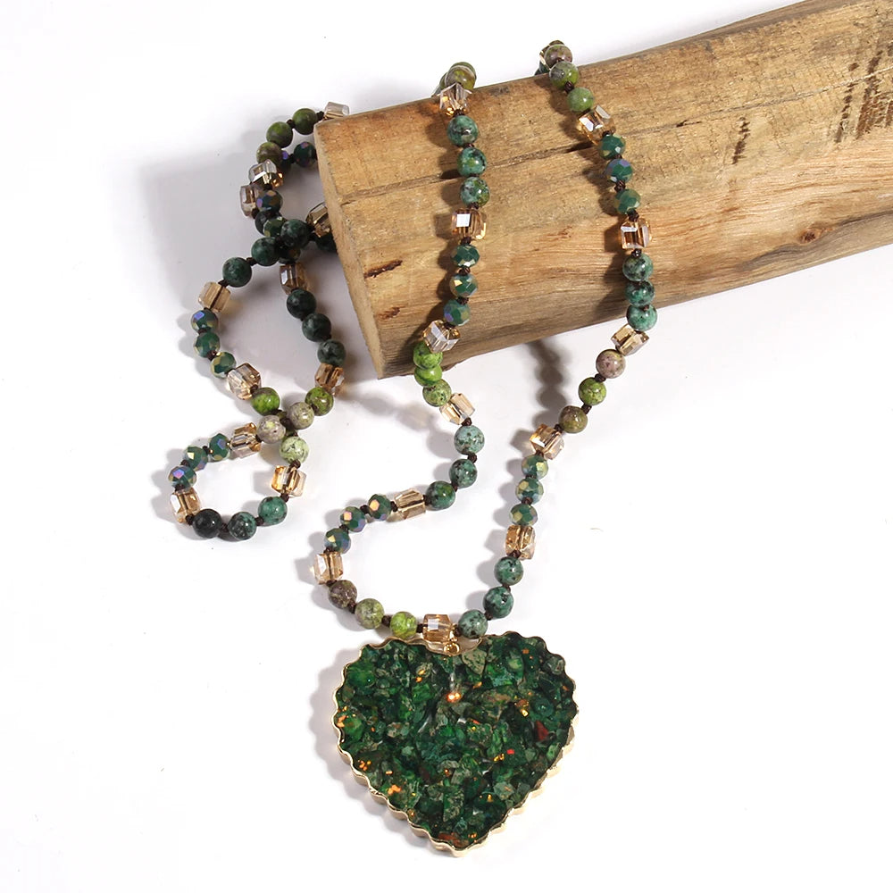 Collier bohème en pierre naturelle avec pendentif en forme de cœur sur un bout de bois sur fond blanc