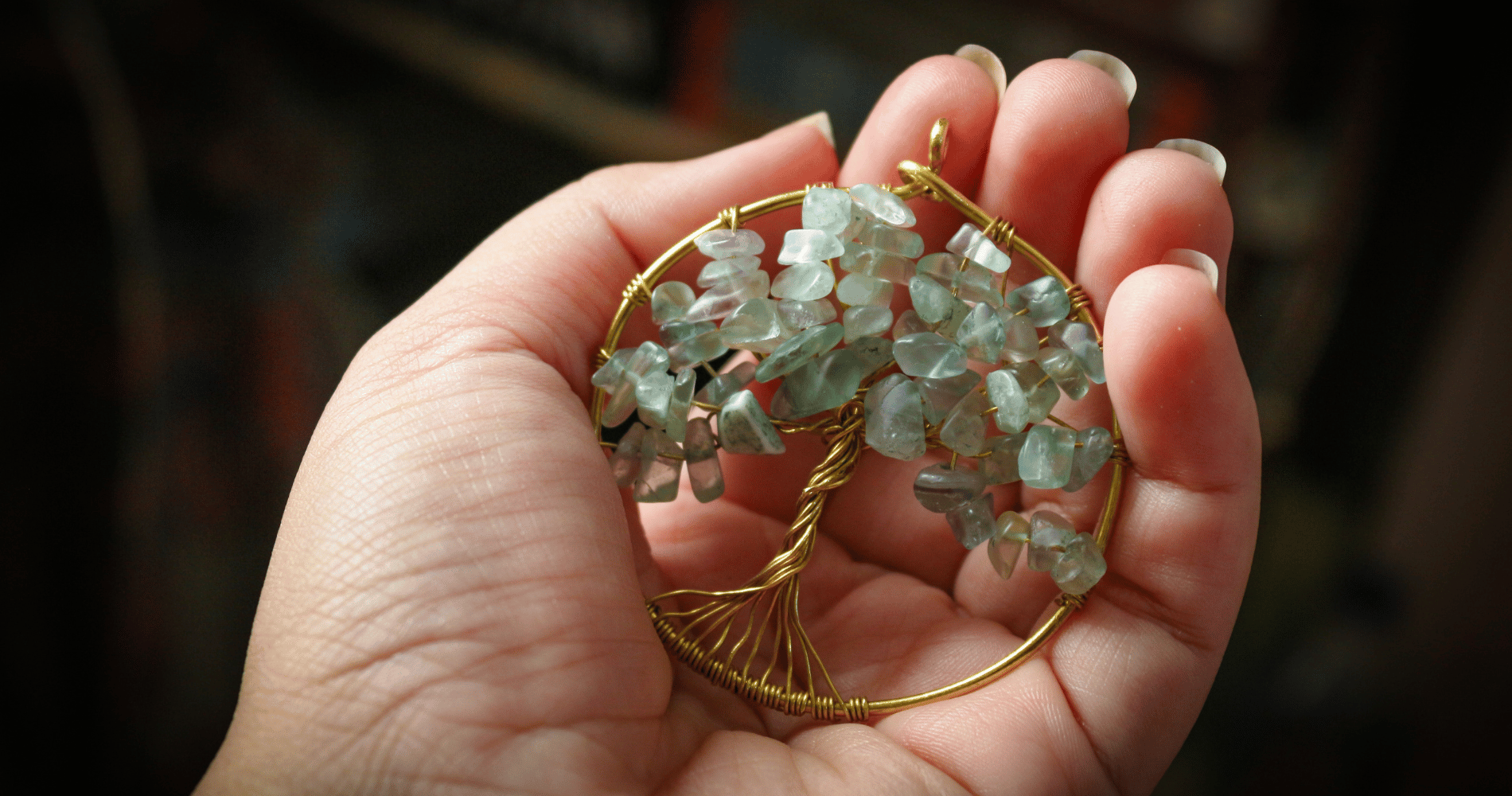 Gros plan sur une main qui tient un pendentif d'arbre de vie 