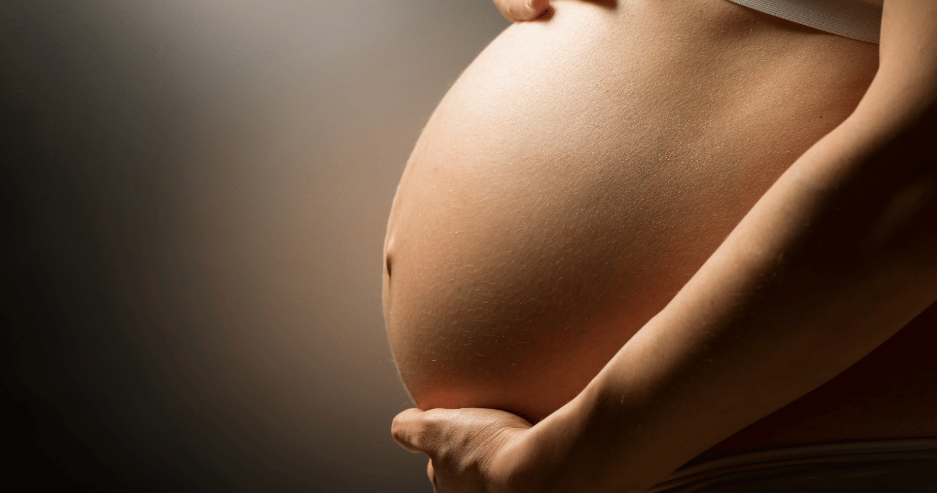 Gros plan sur le ventre d'une maman enceinte grasse aux pierres et cristaux Image