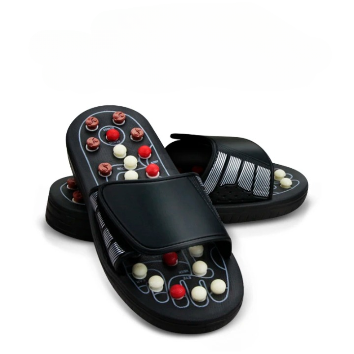 Pantoufles d'acupression noires et massantes sur fond blanc