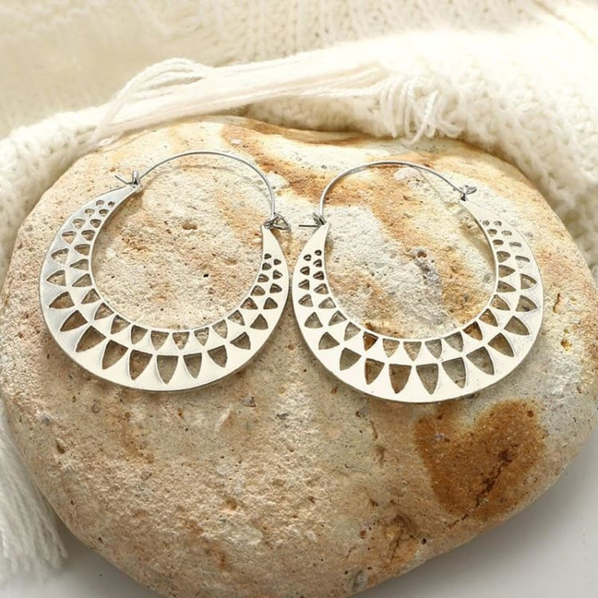 Boucles d'oreilles égyptiennes soleil doré posées sur fond sable
