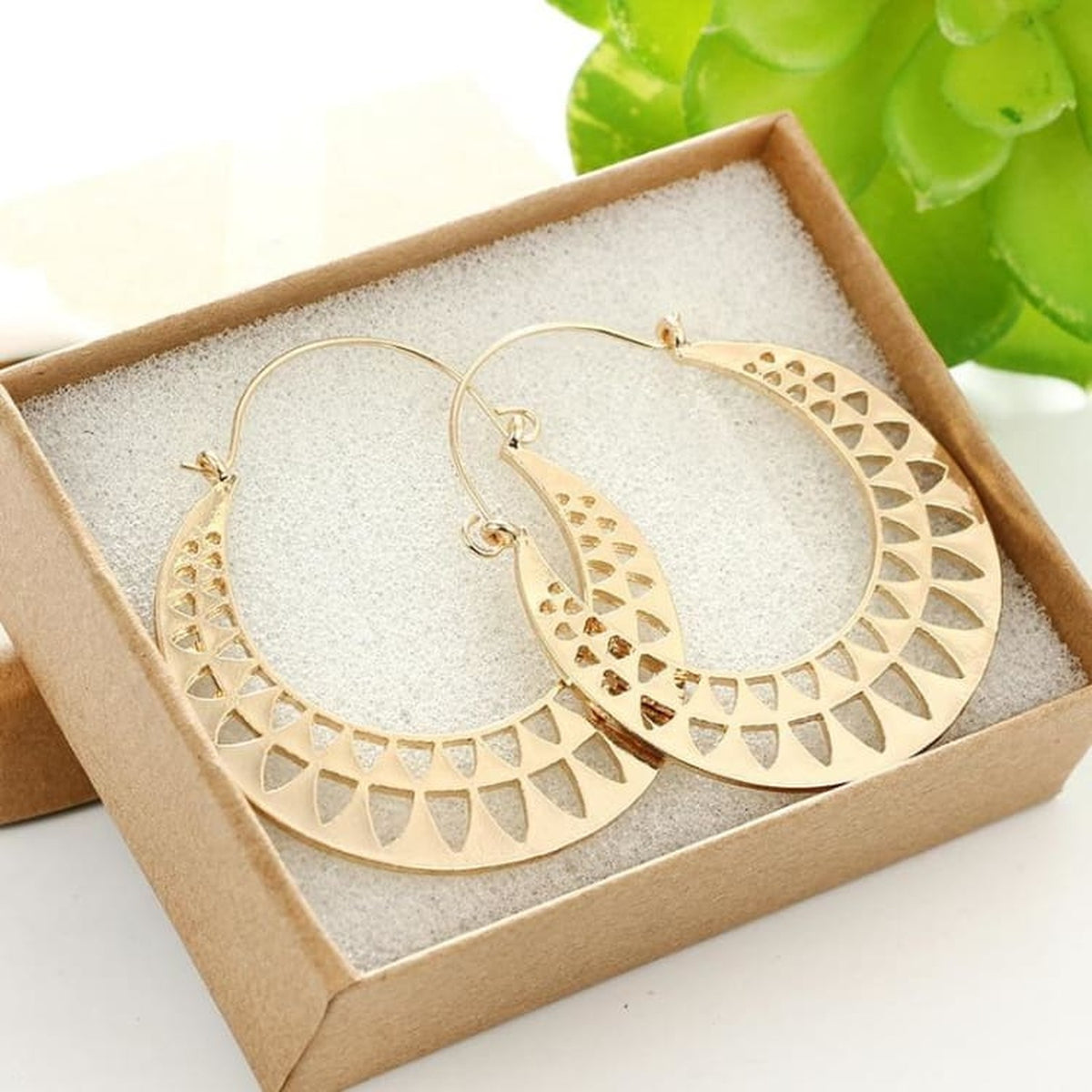 Boucles d'oreilles égyptiennes soleil doré dans un décor végétal
