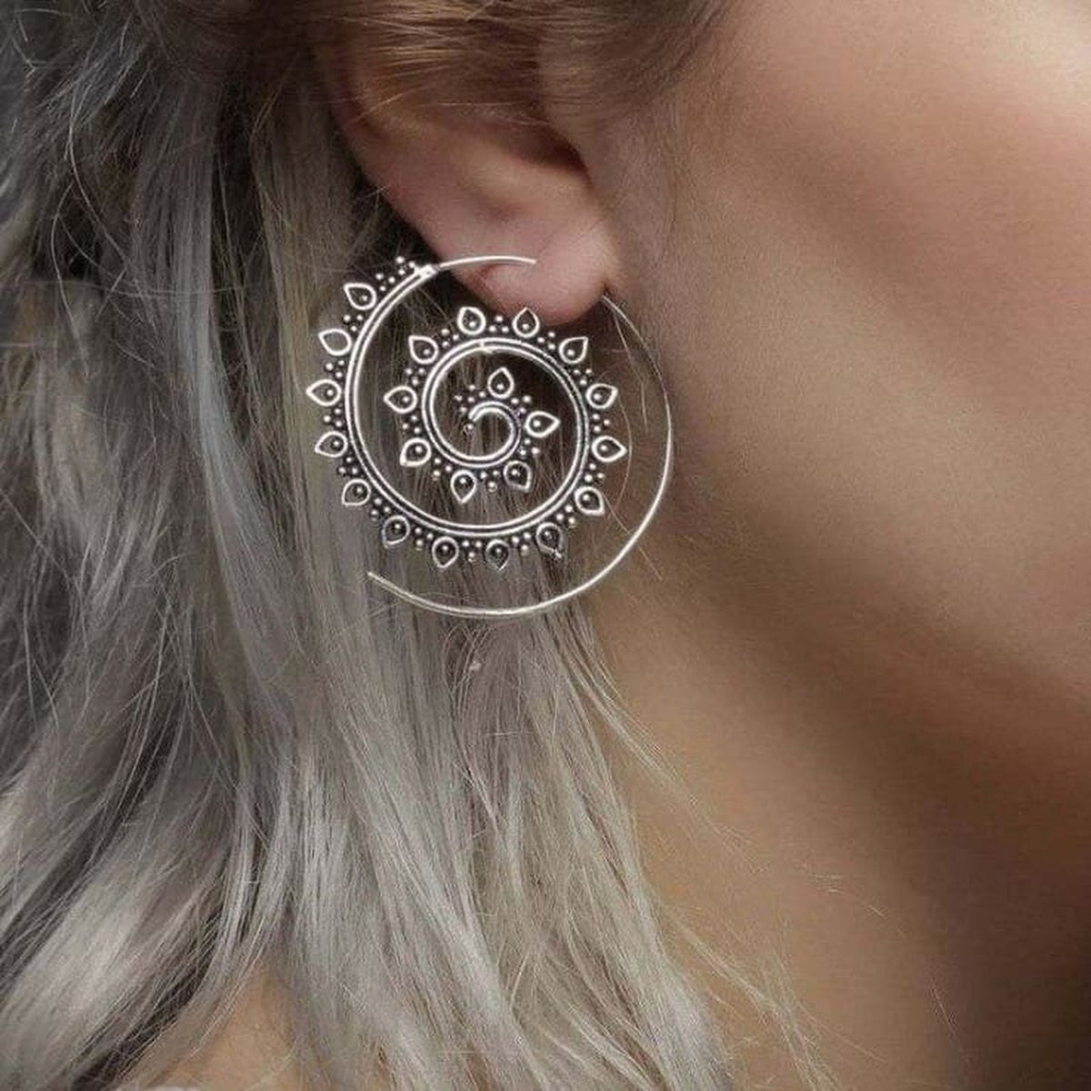 Boucles d'oreilles spirale portées, ambiance chaude, oreille visible