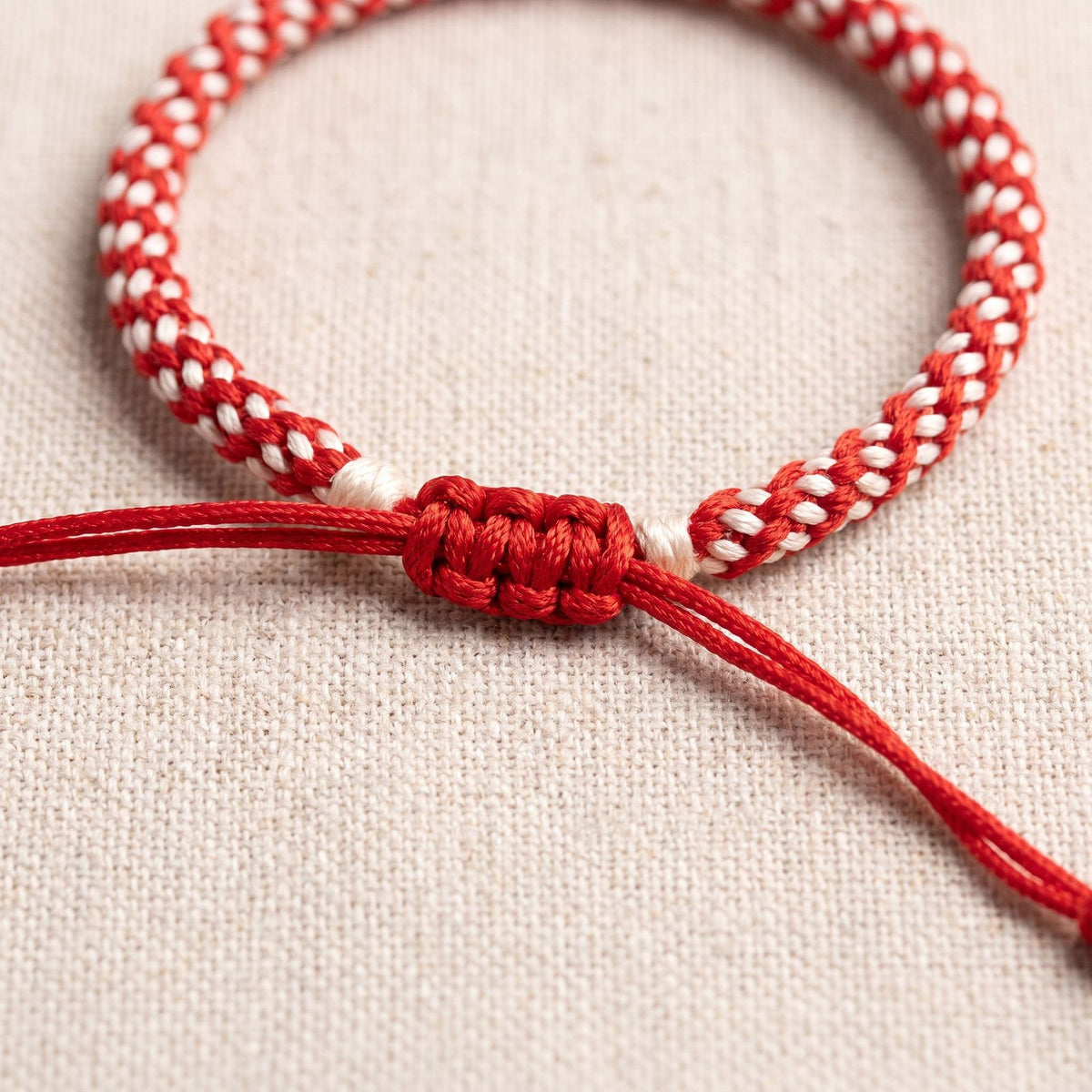 Gros plan du tressage et du noeud coulissant du bracelet des 4 elements rouge et blanc