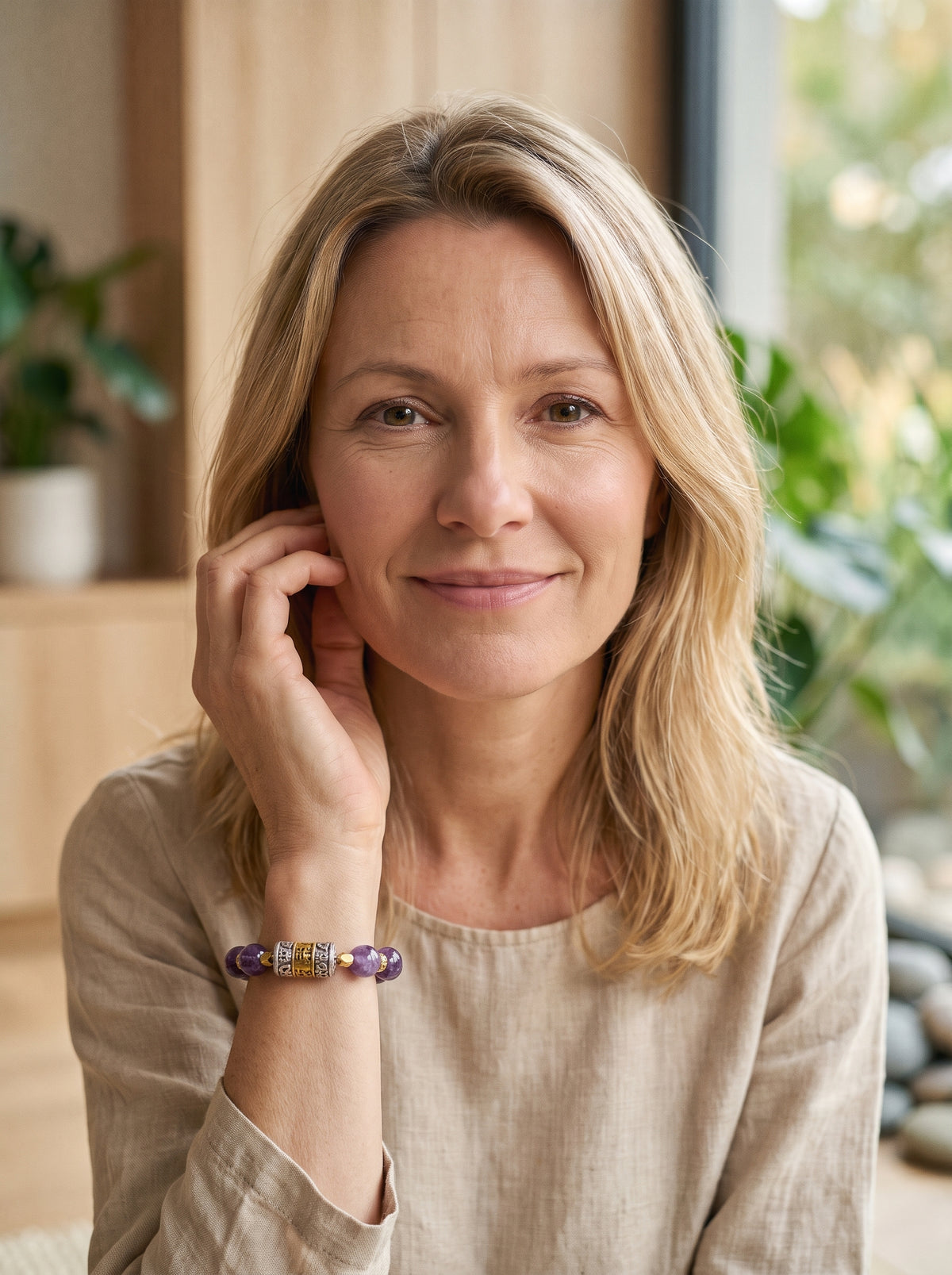 Femme souriante portant le bracelet tibetain Om Mani Padme Hum, perles d'amethyste et cylindre grave au poignet