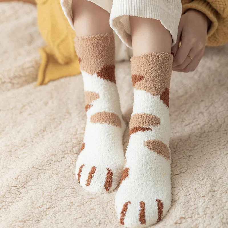 Chaussettes piloulou avec design de patte de chien sur les pieds d'une personne sur fond beige