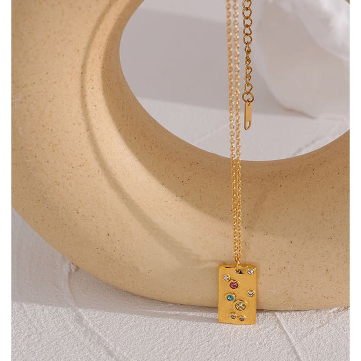 Collier Cassiopée, vue détaillée du pendentif doré à finition martelée, pierres multicolores serties