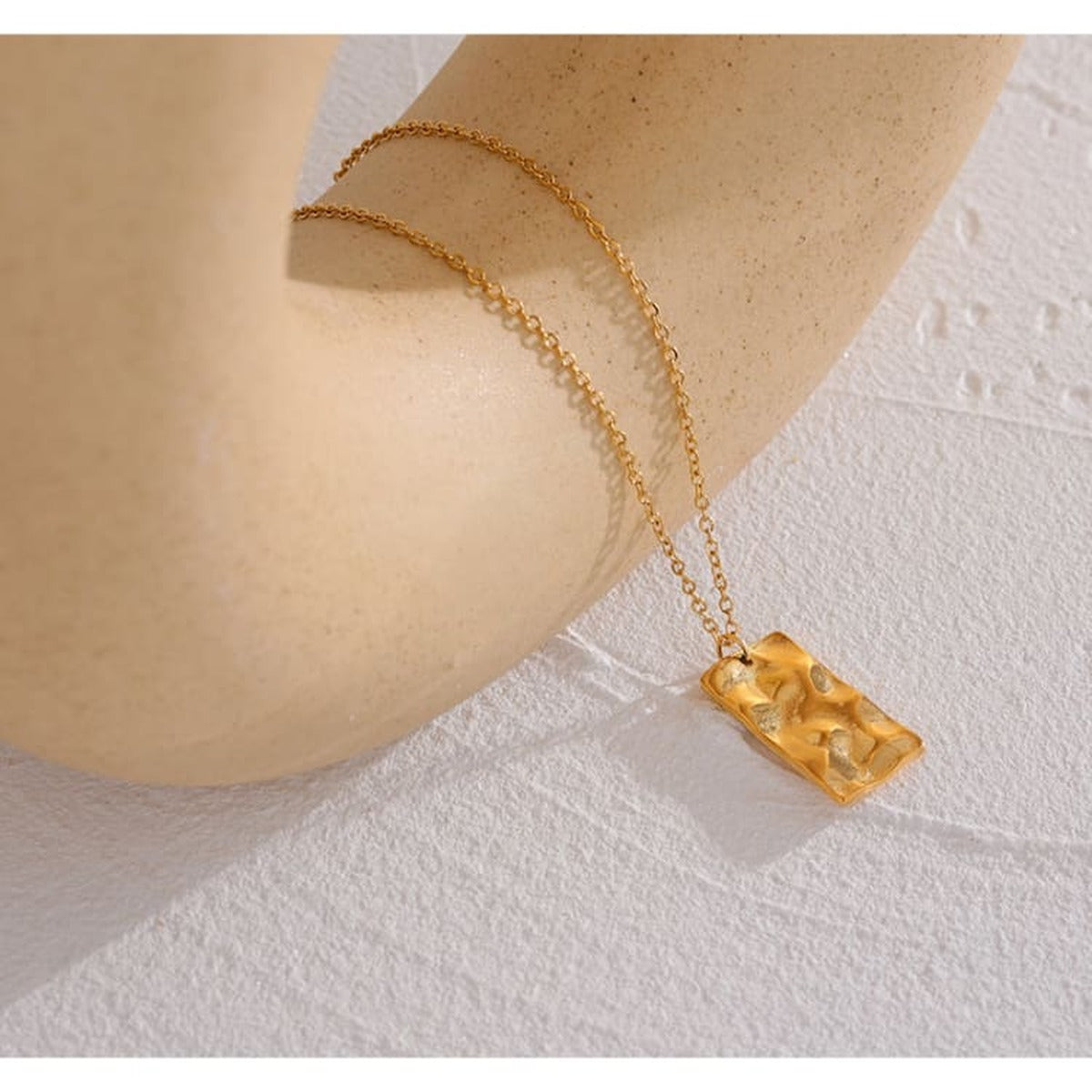 Collier Cassiopée, gros plan du pendentif constellation aux reflets dorés sur fond texturé