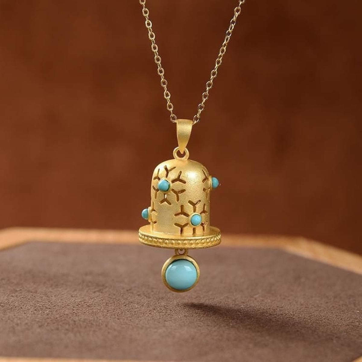 Pendentif cloche dorée et cabochons bleu turquoise, vue de face