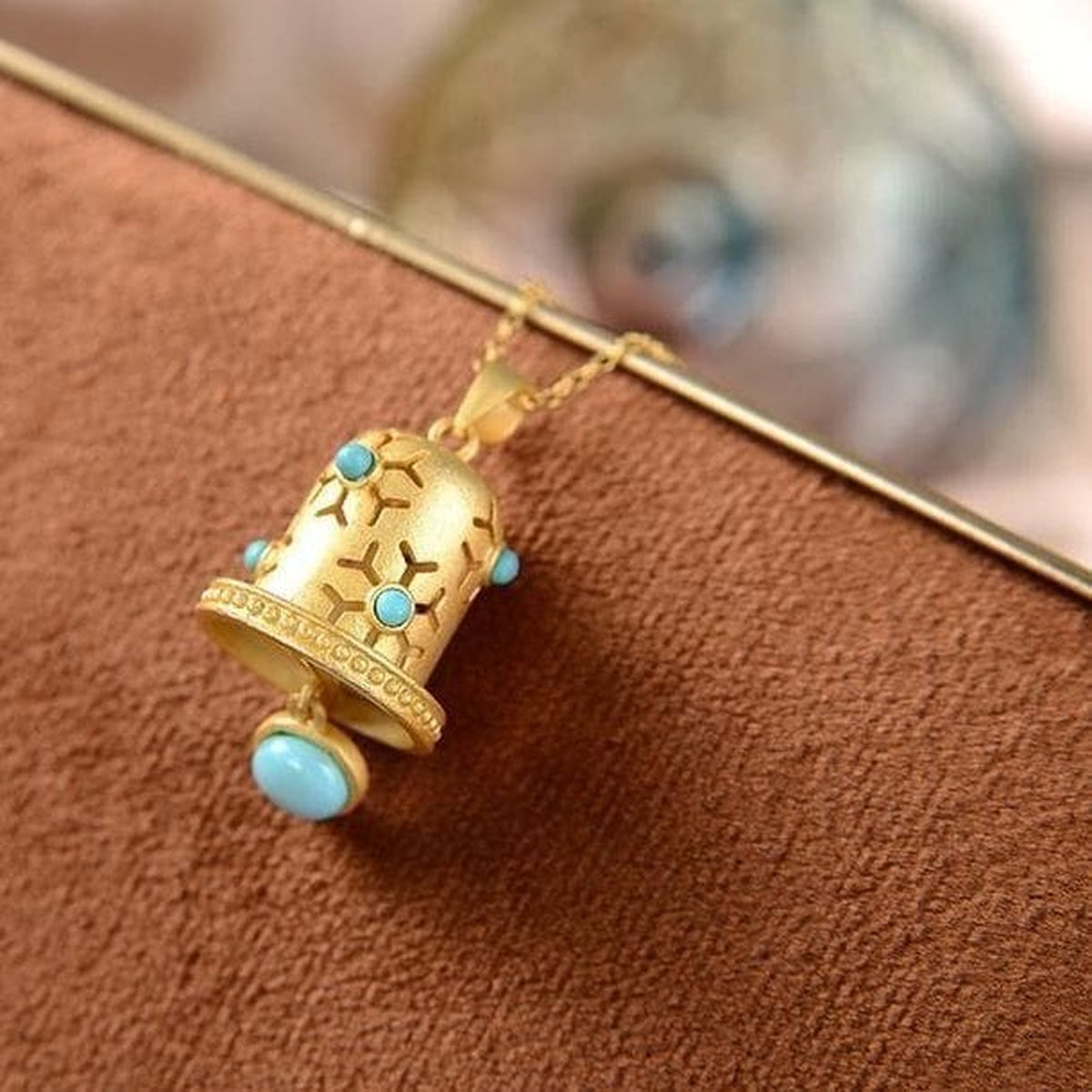 Détail des ajours et cabochons bleu turquoise du pendentif cloche