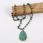Collier de style ethnique en turquoise avec pendentif posé sur un bout de bois sur fond gris