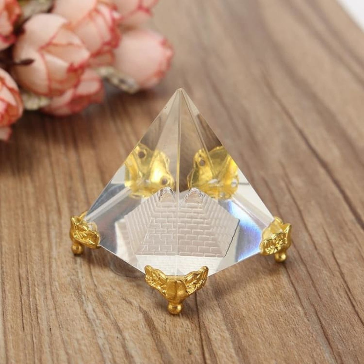 Double pyramide transparente aux détails dorés posée sur une table en bois