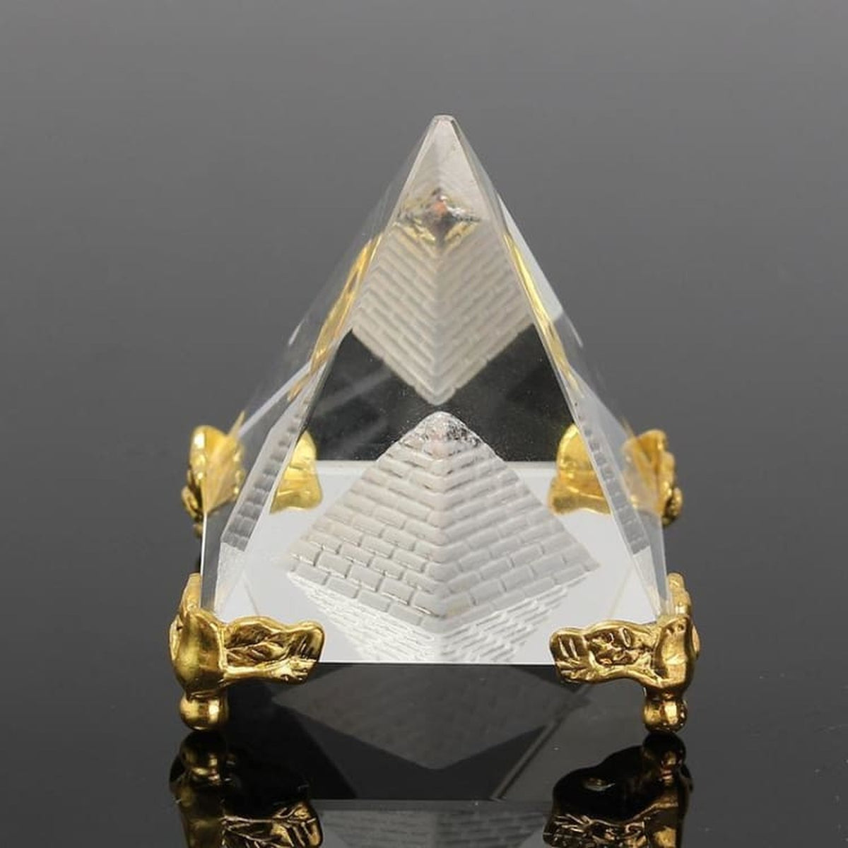Pyramide transparente avec motif interne et détails dorés sur fond sombre