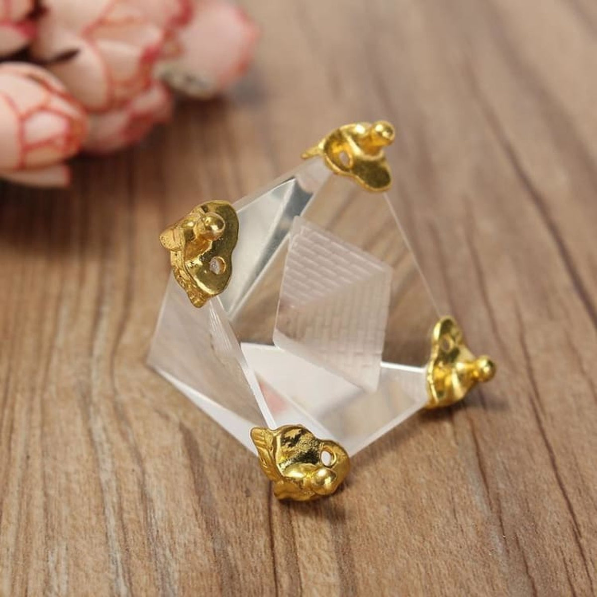 Pyramide transparente facettée vue de trois quarts sur une table en bois