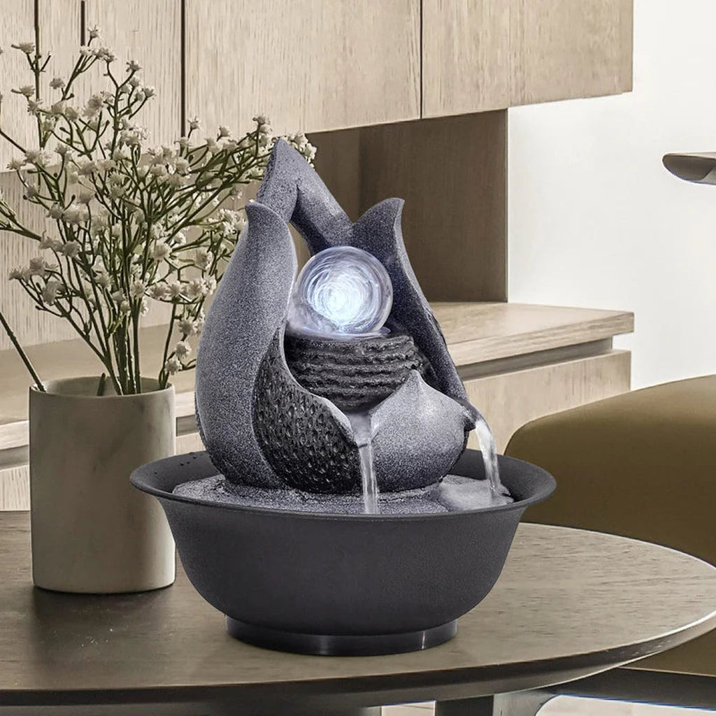 Fontaine décorative grise avec boule lumineuse posée sur une table ronde