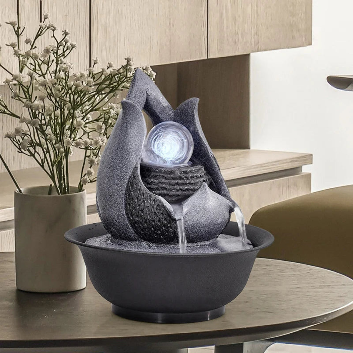 Fontaine décorative grise avec boule lumineuse posée sur une table ronde