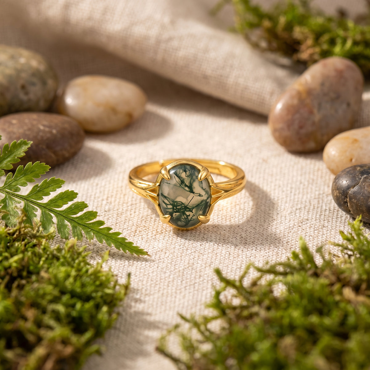 Bague agate mousse posée sur lin avec de la mousse et une fougère