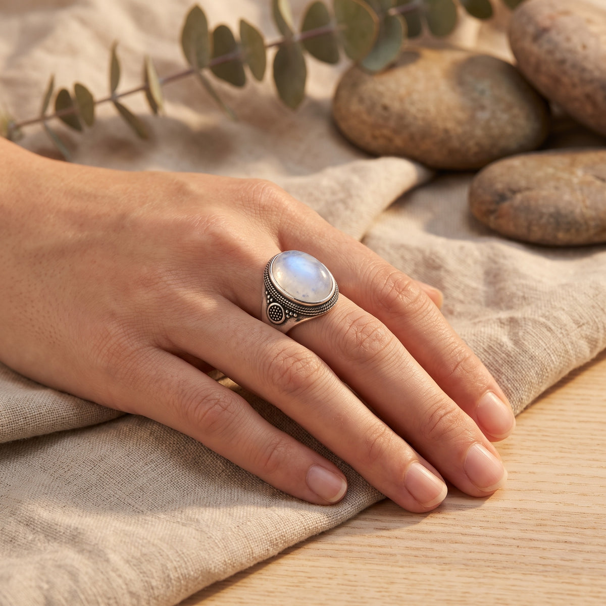 Bague pierre de lune portée au doigt, gros plan sur le grènetis et la rosace