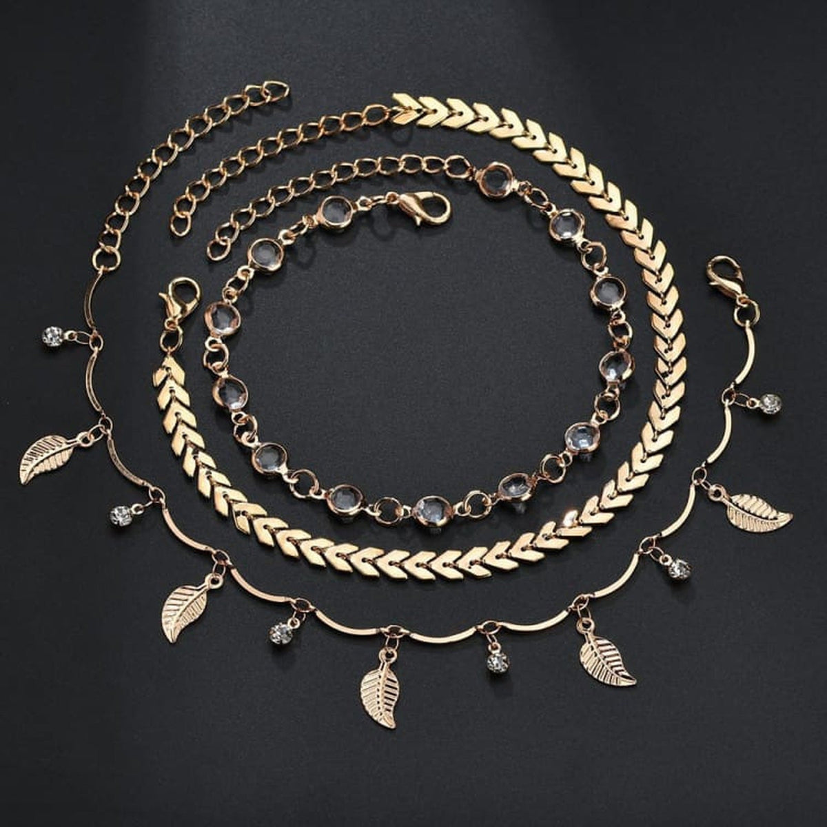 Bracelet de cheville boheme triple rang en presentation circulaire, detail chaine chevron et breloques feuilles