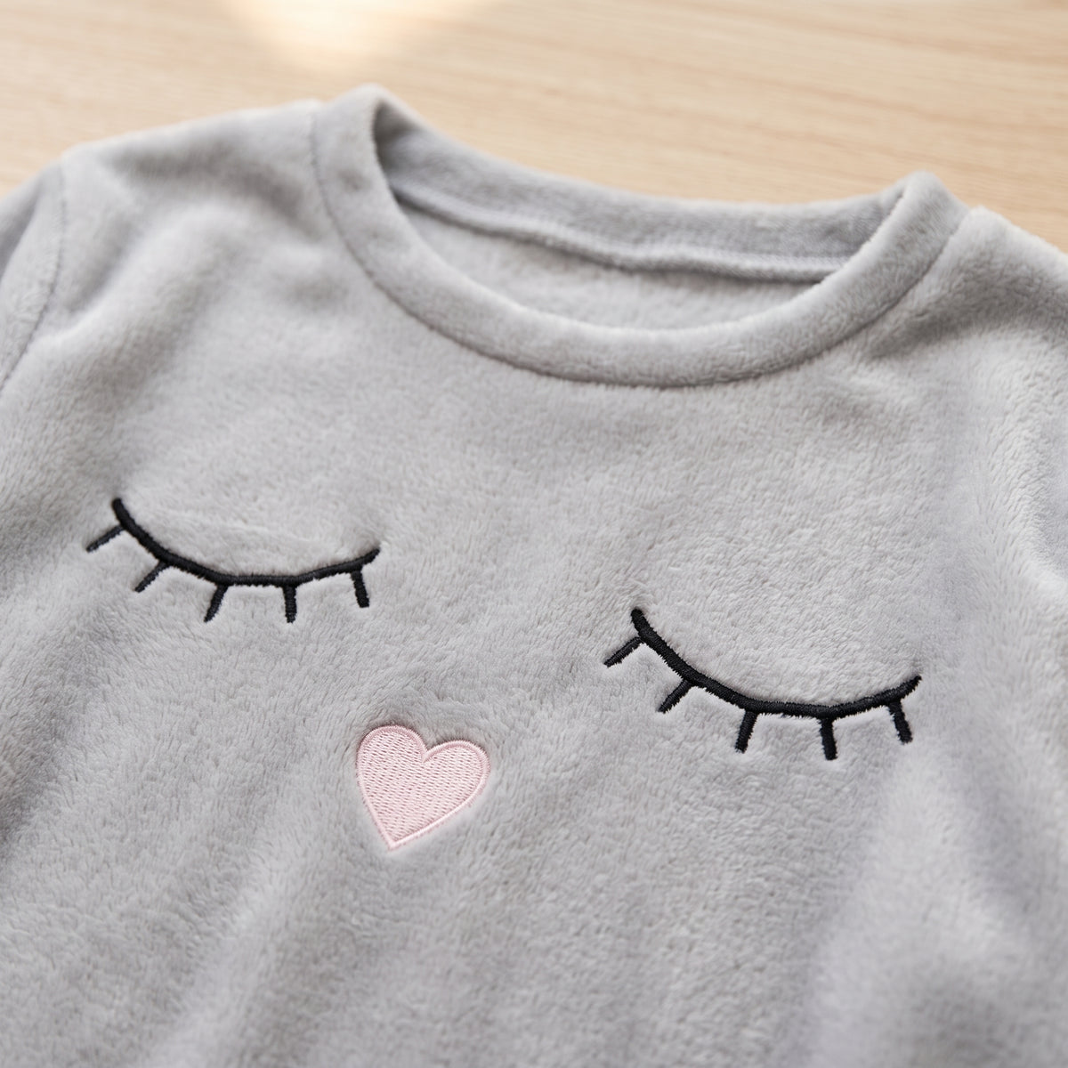 Gros plan sur la polaire moelleuse et la broderie cœur rose du pyjama femme