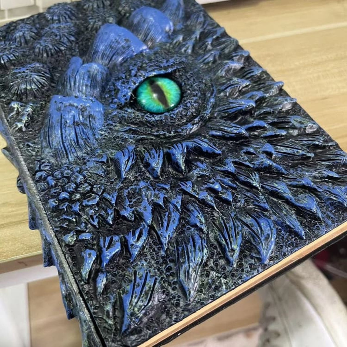 Détail du relief bleu et de l’œil vert du carnet de notes dragon