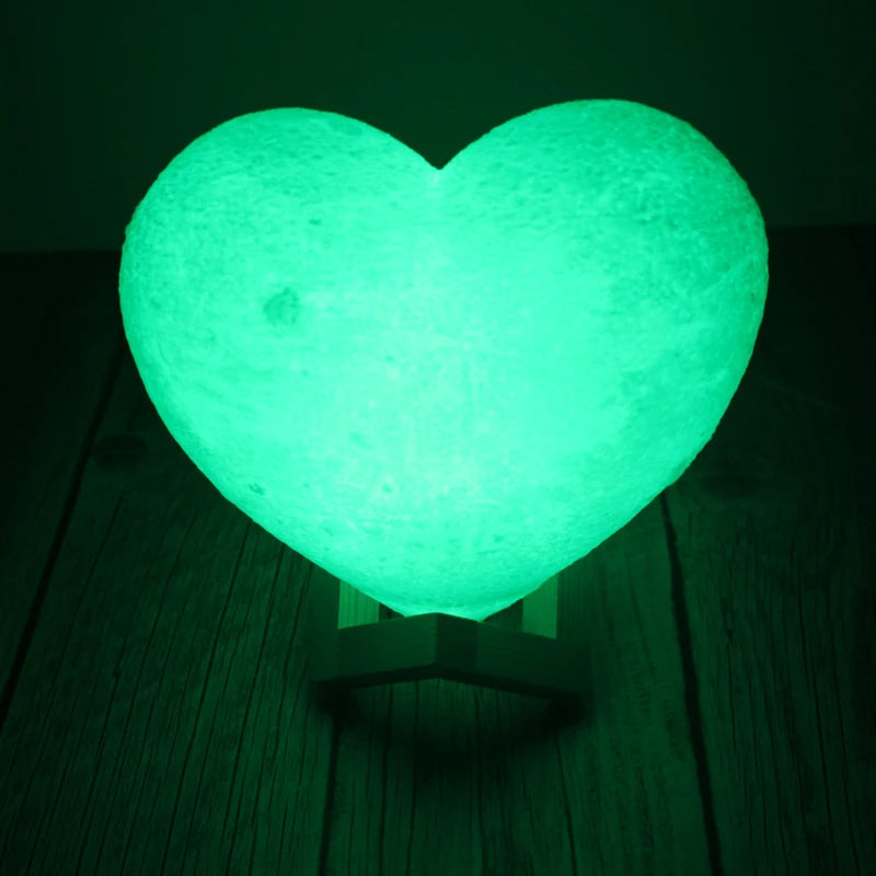 Lampe d'ambiance LED en forme de coeur à couleur variable posée sur une table en bois