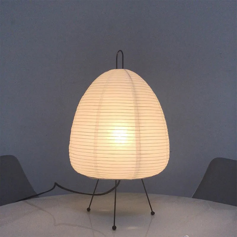 Lampe d'ambiance de style japonais en papier sur trépied sur une table sur fond gris