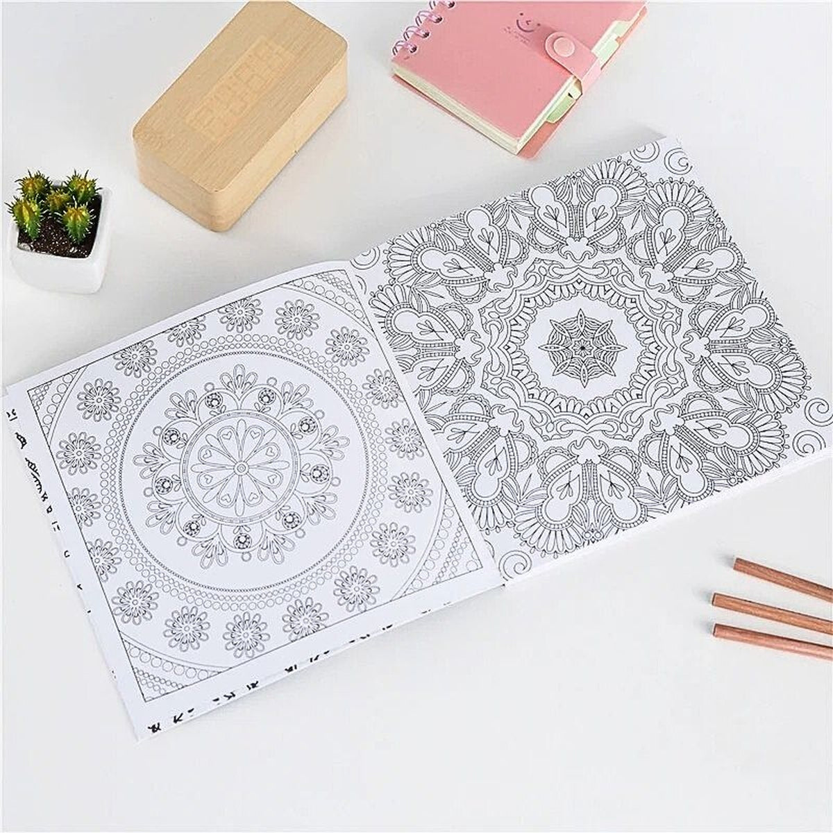 Livre de coloriage mandala ouvert sur une table créative