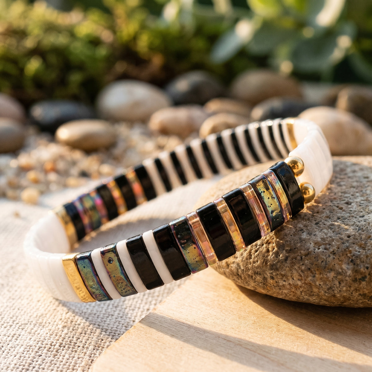 Gros plan perles plates irisées du bracelet en verre japonais, reflets noirs blancs dorés