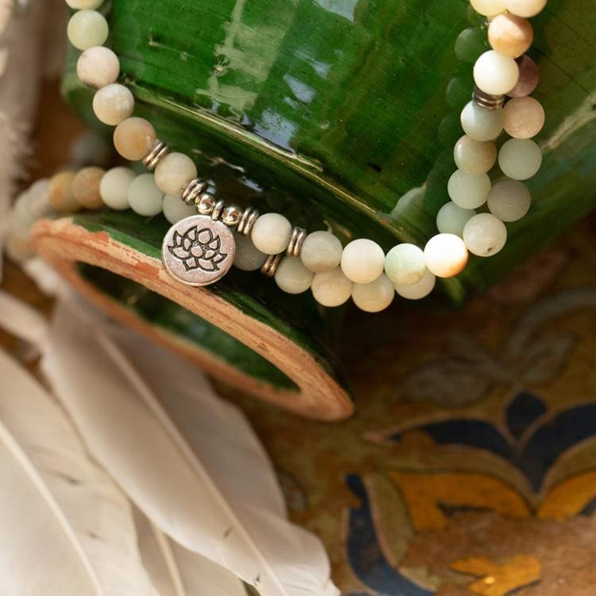 Mâla multicolore avec pendentif Lotus devant un pot vert