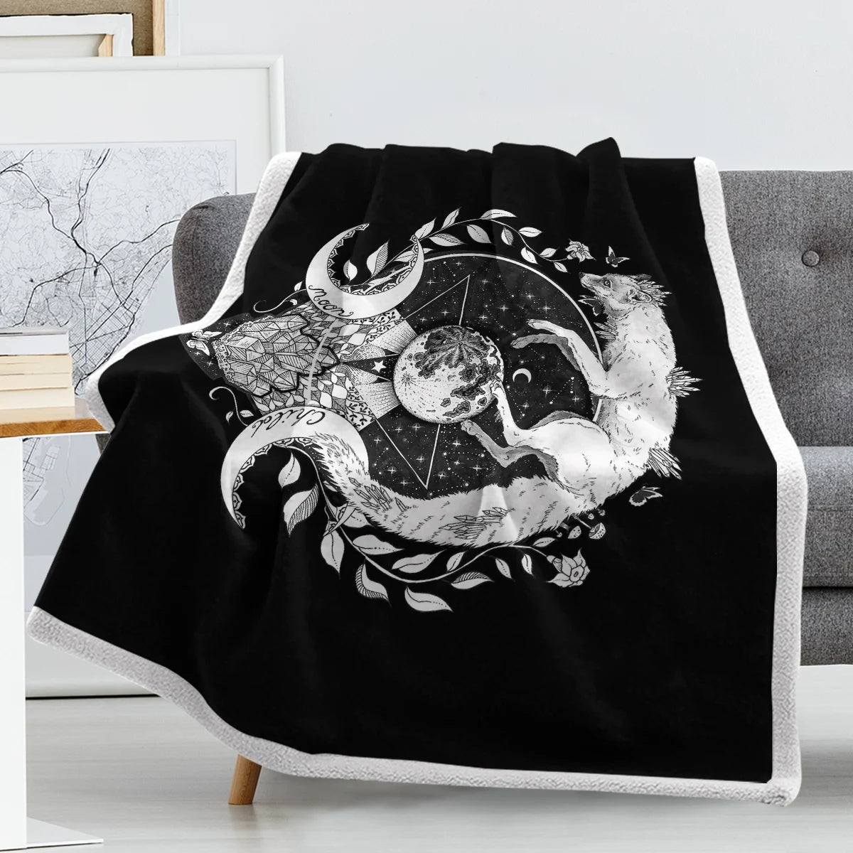 Plaid en sherpa avec imprimé cosmique sur un canapé sur fond gris avec un tableau à gauche