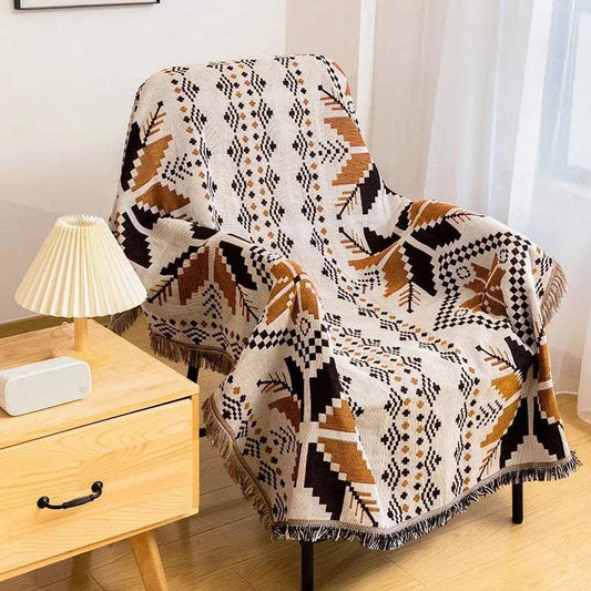 Plaid tribal indien avec formes géométriques sur un fauteuil avec un meuble et une lampe à gauche