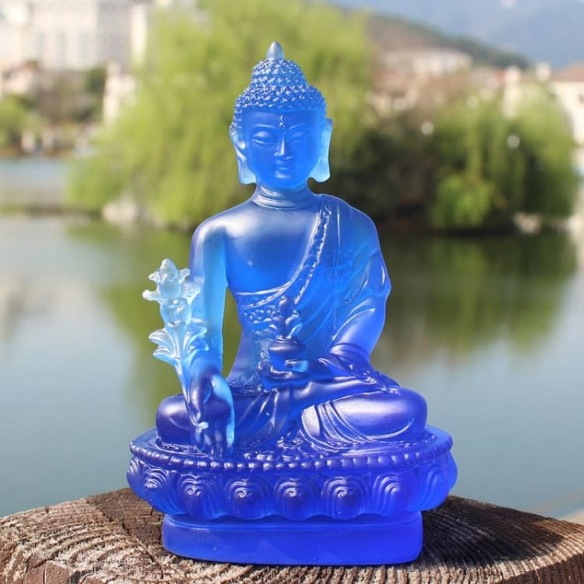 Statuette de Bouddha bleue assise devant un paysage avec lac