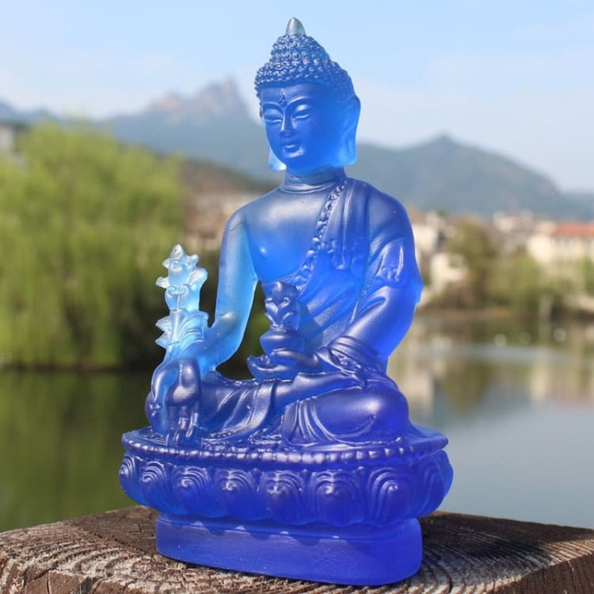 Statuette de Bouddha bleue sur socle lotus vue de face en extérieur