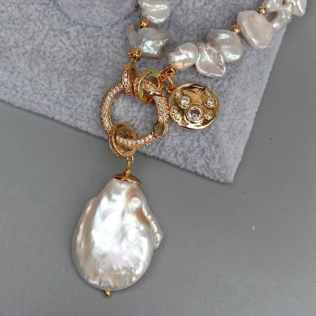 Gros plan macro du pendentif en perle baroque nacrée et du fermoir doré serti