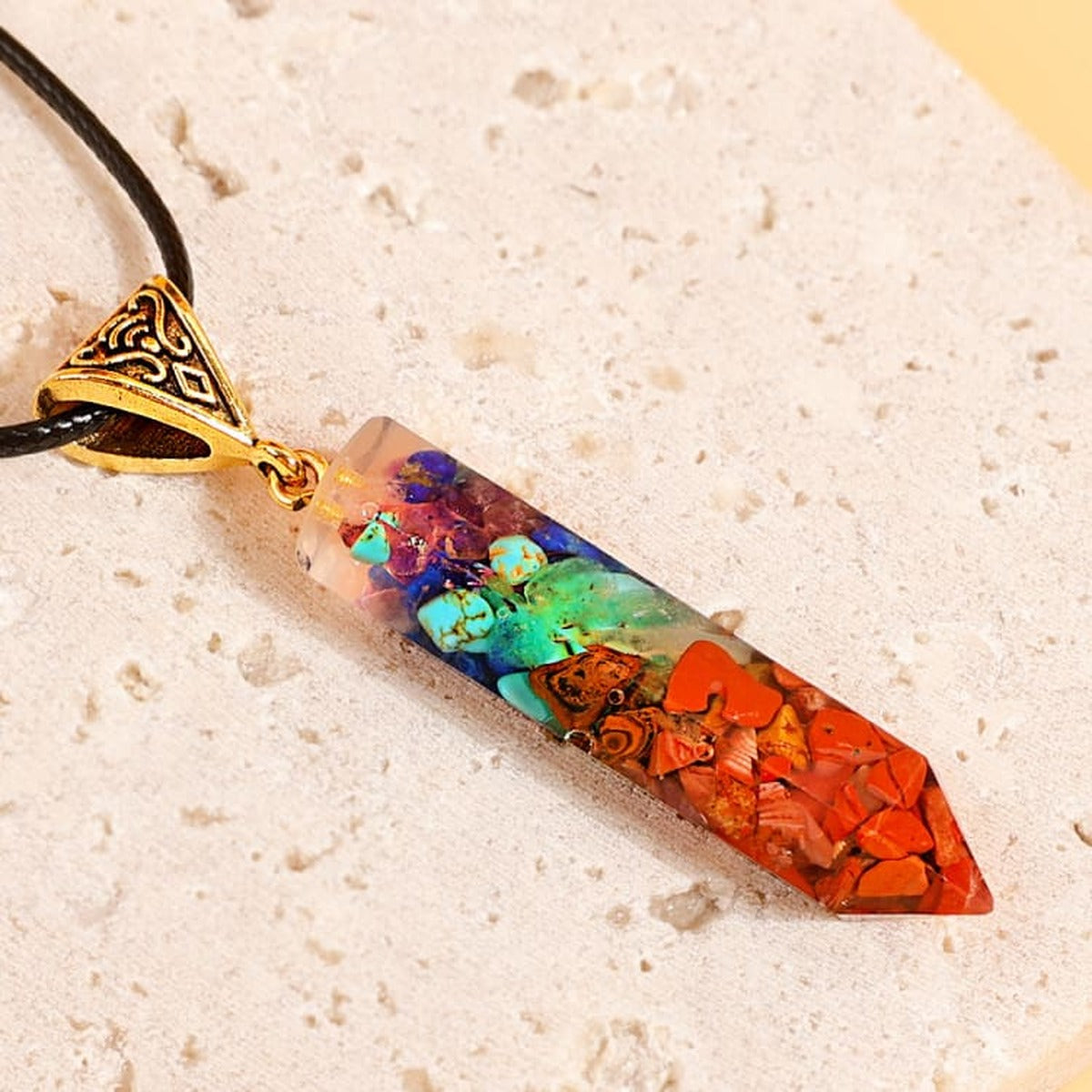 Collier pendentif 7 chakras en pierres naturelles sur fond pierre