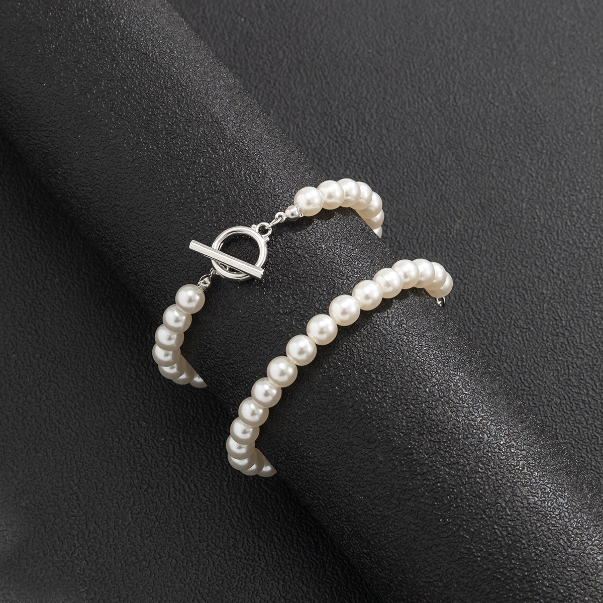 Bracelet de perles blanches enroulé sur présentoir cylindrique noir Image
